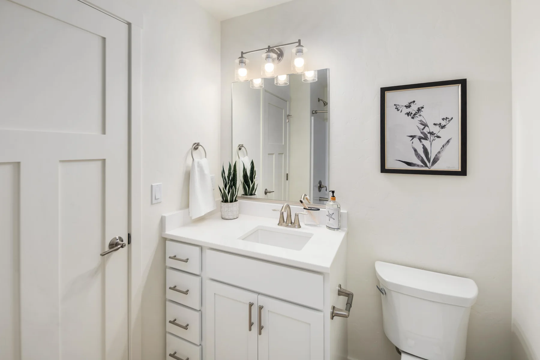 Bathroom with white vanity, mirror, and overhead lighting